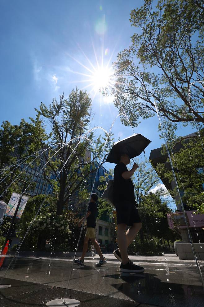 전국 대부분 지역에 폭염경보가 발효된 2025년 7월27일 오후 서울 종로구 광화문광장 분수터널을 한 시민이 양산을 쓰고 지나가고 있다. 김혜윤 기자 unique@hani.co.kr