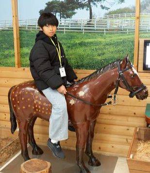 모형 말에 올라타 고삐를 잡고 포즈를 취한 곽준혁 학생기자.