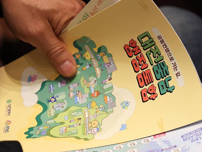 A person looks over promotional materials for the proposed administrative merger of Daejeon and South Chungcheong during a briefing session and civic unity rally held at the main auditorium of Daejeon City Hall on Dec. 12, 2025. [NEWS1]
