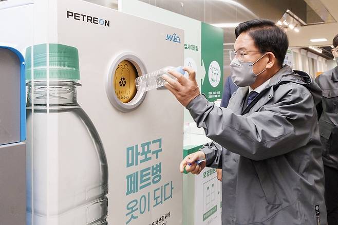 박강수 마포구청장이 페트병 업사이클링 통에 빈 병을 넣고 있다.