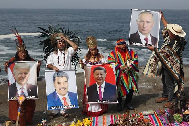 2025년 12월 29일(현지시간) 페루 리마 태평양 연안에서 주술사들과 치유사들이 세계 각국 지도자들의 사진을 들고 새해를 앞둔 전통 의식을 진행하고 있다. EPA 연합뉴스