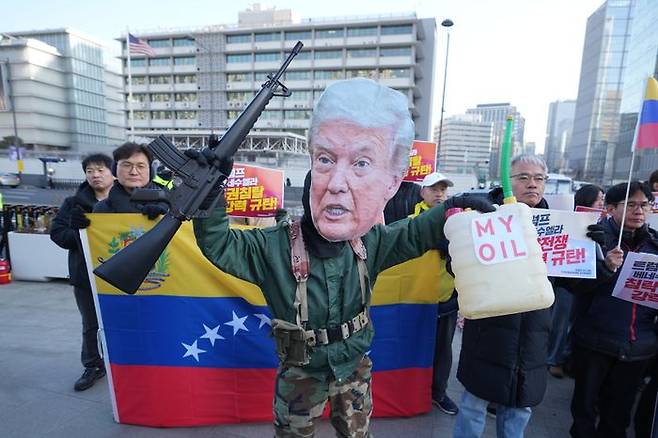 도널드 트럼프 미국 대통령의 가면을 쓴 남성이 5일 서울 주한미국대사관 앞 광화문광장에서 모형 총을 들고 미국의 베네수엘라 침공을 규탄하는 시위를 벌이고 있다(자료사진). ⓒAP/뉴시스