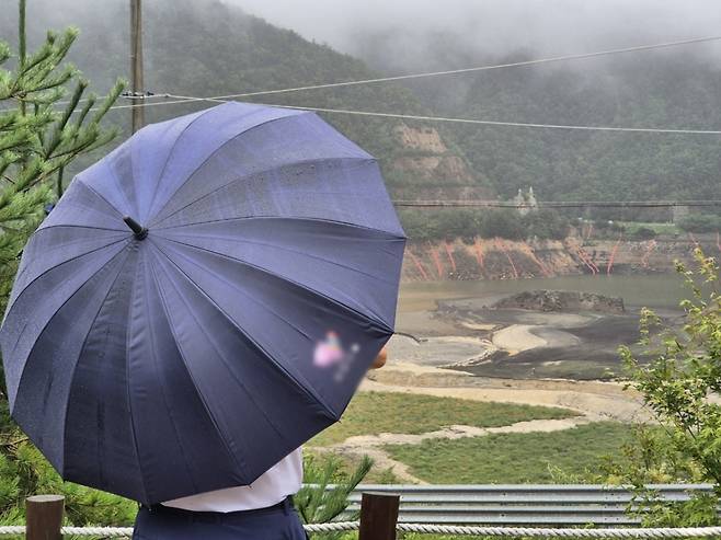 강원 강릉지역에 많은 비가 내린 9월13일 오전 우산을 쓴 시민이 마른 저수지에 내리는 단비를 바라보고 있다./사진=뉴스1.