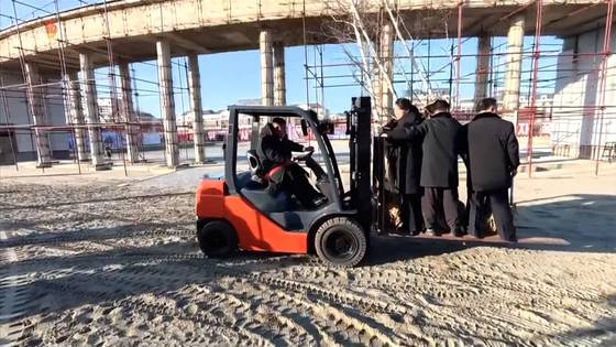 김정은 북한 국무위원장이 지난 5일 '해외군사작전 전투위훈기념관' 건설 현장에서 지게차를 직접 운전하며 주애와 당·정부 지도간부들을 태우고 이동하고 있다. 조선중앙TV=연합뉴스