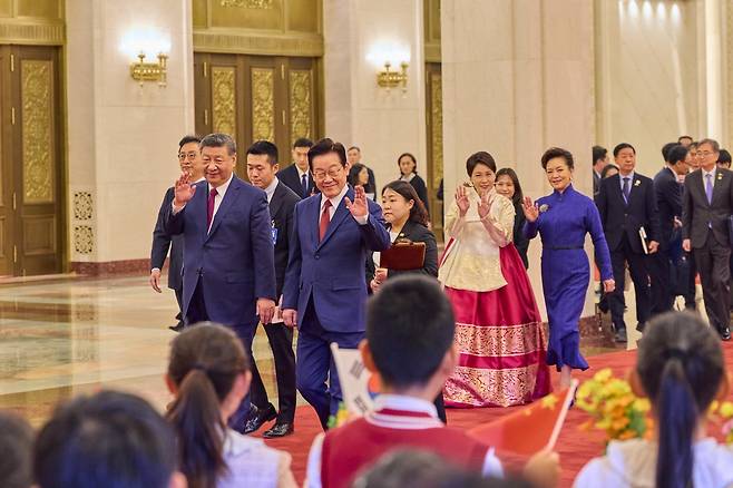 중국을 국빈 방문 중인 이재명 대통령과 김혜경 여사가 5일(현지 시간) 베이징 인민대회당에서 열린 공식환영식에서 시진핑 국가주석, 부인 펑리위안 여사와 이동하며 환영 나온 어린이들에게 인사하고 있다. 뉴시스