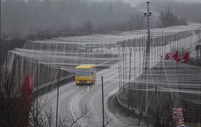 지난해 12월12일 우크라이나의 하르키우 지역의 이줌. 드론 방어 그물로 뒤덮힌 도로를 한 버스가 운행하고 있다. 로이터 연합뉴스