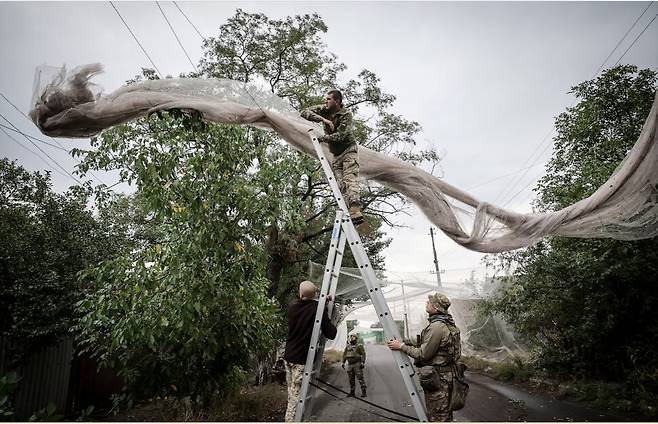 지난해 9월19일 우크라이나 도네츠크의 코스티안티니우카. 우크라이나군 병사들이 도로에 드론 방어 그물을 설치하고 있다. 로이터 연합뉴스