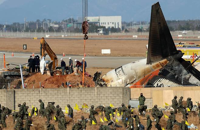Officials from a joint investigation team retrieve an engine buried at the Jeju Air crash site at Muan International Airport in South Jeolla on Jan. 2, 2025. [YONHAP]