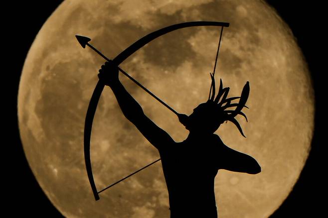 3일(현지시각) 미국 캔자스주 토피카에 있는 주청사 꼭대기의 ‘아드 아스트라(Ad Astra)’ 조각상 뒤로 보름달이 떠오르고 있다. 토피카/AP 연합뉴스