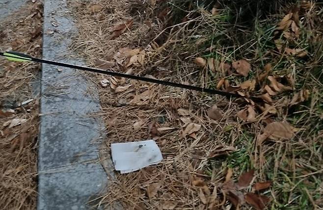 An arrow is seen lodged in a flower bed just meters from where a woman had been walking her dog. (Yonhap)
