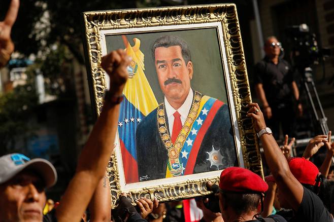 People carry a portrait of Venezuela's President Nicolas Maduro as they attend a march calling for his release, after he and his wife Cilia Flores were captured following U.S. strikes on Venezuela, in Caracas, Venezuela, on Jan. 4. [REUTERS/YONHAP]