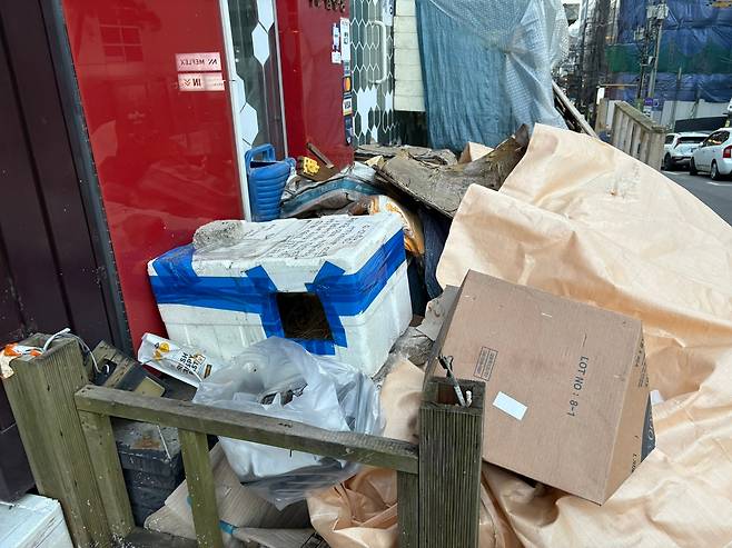 /정동하 기자1월 4일 오후 서울 서대문구 이대 거리 한 공실 상가 앞. 가게에서 버린 폐기물들과 무단 투기된 생활 쓰레기들 위에 포대 자루가 덮여 있다.