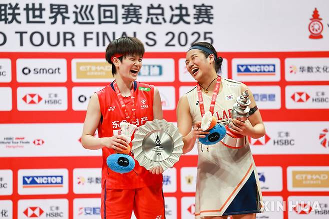 [항저우=신화/뉴시스] 안세영(오른쪽)이 21일(현지 시간) 중국 저장성 항저우 올림픽스포츠센터에서 열린 2025 세계배드민턴연맹(BWF) 월드투어 파이널스 여자 단식 정상에 올라 시상대에서 왕즈이(중국)와 함께 웃으며 포즈를 취하고 있다. 안세영은 결승에서 왕즈이를 2-1(21-13 18-21 21-10)로 꺾고 우승하며 시즌 11승을 달성했다. 2025.12.22.