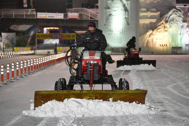 ▲ 10일 오후부터 밤새 내린 눈을 치우기 위해 화천산천어축제장에서 11일 새벽 화천군청 공무원들과 축제관계자들이 제설작업을 실시하고 있다.