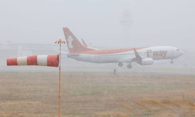 제주국제공항에 강풍특보와 급변풍특보가 내려진 11일 오전 한 항공기가 눈보라를 뚫고 활주로에 착륙하고 있다. 연합뉴스