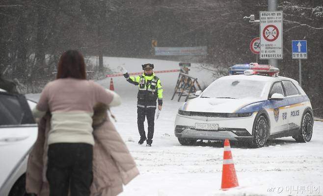 [제주=뉴시스] 우장호 기자 = 제주 산지·중산간·동부·남부에 대설특보가 내려진 11일 오전 제주시 어승생 삼거리 입구에서 제주서부경찰서 소속 경찰관이 도로통제를 하고 있다.   기상청에 따르면 제주도는 12일까지 한라산 등 고지대를 중심으로 최대 15㎝의 눈이 내려 쌓일 것으로 예측됐다. 2026.01.11. woo1223@newsis.com /사진=우장호