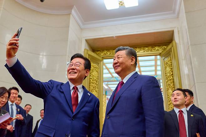 President Lee Jae Myung, on a state visit to China, takes a selfie with President Xi Jinping using a Xiaomi smartphone that Xi presented to him at the Gyeongju summit, after an official banquet at the Great Hall of the People in Beijing on Jan. 5 (local time). [JOINT PRESS CORPS]