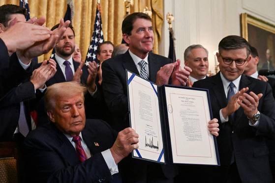 U.S. President Donald Trump holds the signed ″Genius Act″, which will develop regulatory framework for stablecoin cryptocurrencies and expand oversight of the industry, at the White House in Washington, D.C., U.S., July 18, 2025. [REUTERS/ YONHAP]