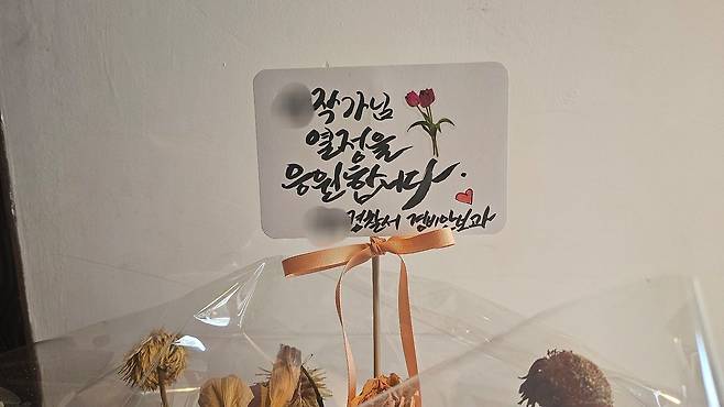 A 서장이 이끄는 경찰서 직원들이 부서 명의로 전시장에 보낸 축하 화분. 사진 독자