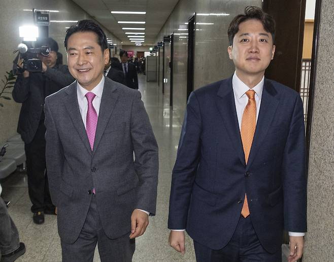 Reps. Jang Dong-hyeok (left) and Lee Jun-seok, who chair the People Power Party and Reform Party, respectively, walk side by side at the National Assembly in Seoul on Tuesday. (Yonhap)