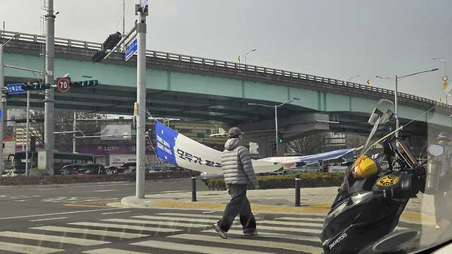 지난 주말 강풍으로 뒤집힌 현수막이 보행자들의 통행을 위협하고 있다. 독자 제공