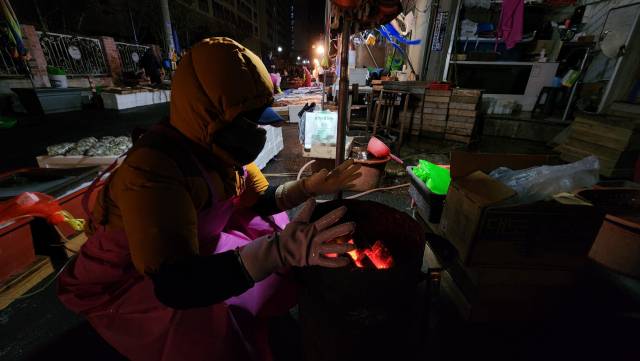 마산어시장의 한 상인이 모닥불에 손을 녹이고 있다.