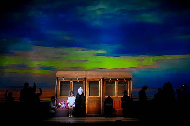 '센과 치히로의 행방불명'공연 모습. '치히로'와 '가오나시'가 전차를 타고 '제니바'를 찾아 가고 있다. 사진 TOHO Theatrical Dept.