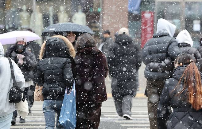 People walk through the snow near Gangnam Station in Gangnam District, southern Seoul, on Jan. 12. [YONHAP]