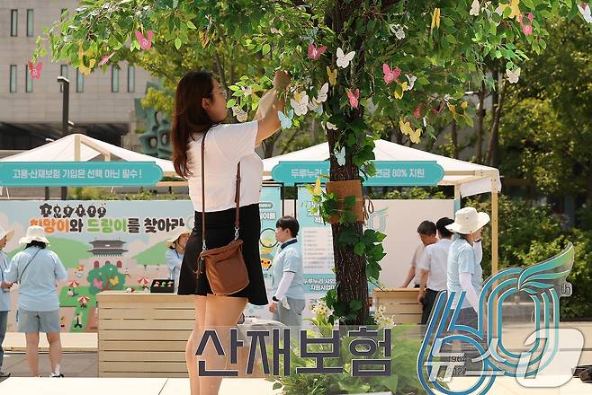 지난 2024년 서울 광화문광장에서 열린 근로복지공단 산재보험 60주년 기념행사를 찾은 시민이 희망나무 이벤트에 참여하고 있다. 2024.6.28/뉴스1 ⓒ News1 김진환 기자