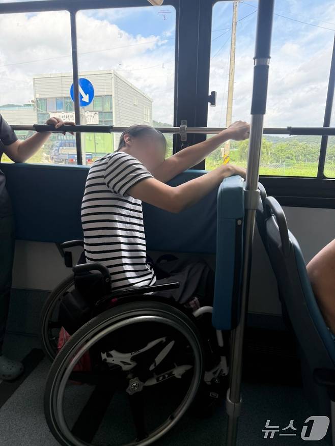 김해 저상버스 이용 실태 모니터링에 참여한 장애인 활동가가 휠체어 안전 장치가 지원되지 않는 저상버스를 탑승해 팔로 휠체어를 고정하고 있는 모습.(김해서부장애인인권센터 제공. 재판매 및 DB금지)