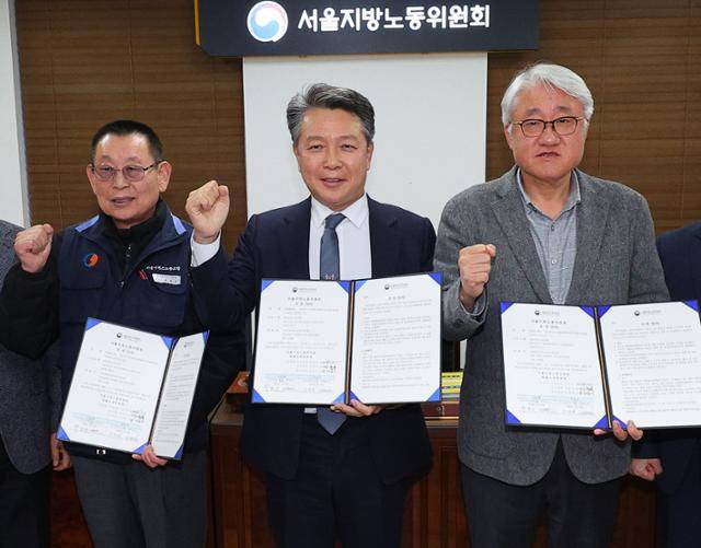 15일 서울 영등포구 서울지방노동위원회에서 열린 특별조정위원회 2차 사후 조정회의에서 박점곤(맨 왼쪽) 서울시버스노동조합 위원장과 사측인 김정환(맨 오른쪽) 서울시버스운송사업조합 이사장을 비롯한 참석자들이 노사 합의를 마치고 기념촬영을 하고 있다. 연합뉴스