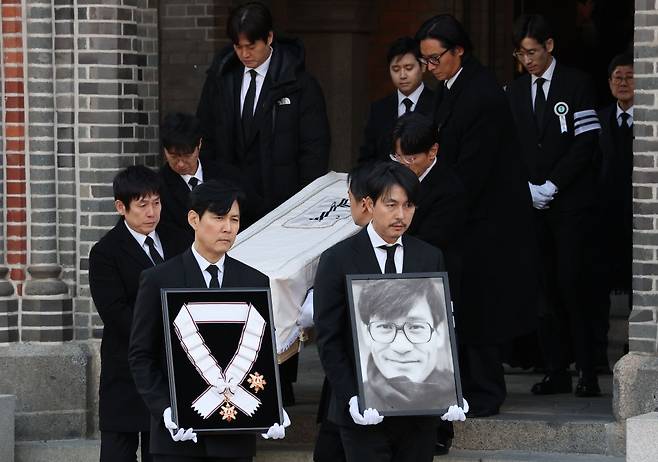 9일 서울 중구 명동성당에서 배우 안성기의 장례 미사가 끝난 뒤 고인의 영정과 금관문화훈장을 든 배우 정우성(오른쪽), 이정재가 영결식장으로 향하고 있다. 연합뉴스