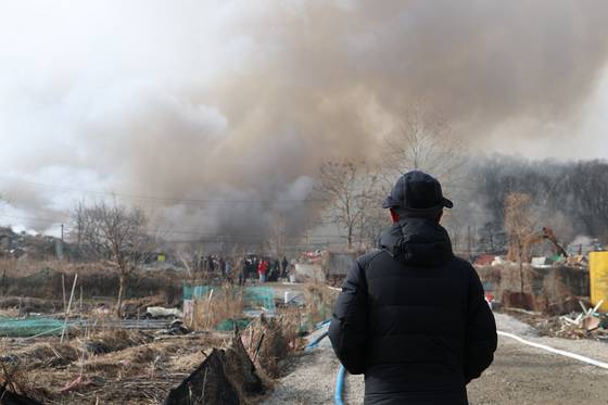 16일 서울 강남구 개포동 구룡마을 4지구 화재현장 소방 통제선 밖에서 주민이 현장을 지켜보고 있다. 〈사진=연합뉴스〉