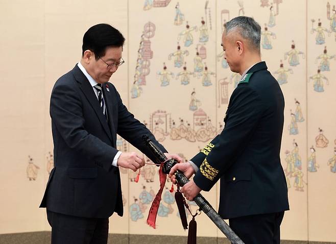 이재명 대통령이 16일 청와대 본관에서 열린 3성 장군 진급·보직 신고 및 수치 수여식에서 어창준 수도방위사령관의 삼정검에 수치를 달아주고 있다. 연합뉴스