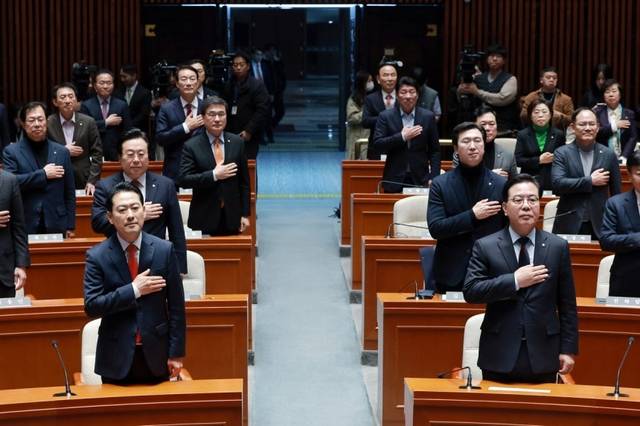 장동혁 국민의힘 대표와 송언석 원내대표가 15일 국회에서 열린 의원총회에 참석해 국기에 경례하고 있다. 연합뉴스