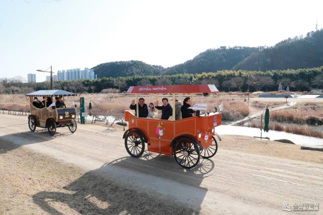 김두겸 울산시장과 시민들이 지난 14일 태화강 국가정원에서 열린 ‘울산 마차’ 시승회에 참석해 손을 흔들고 있다. 오는 3월부터 본격 운영되는 전기 마차는 지면에서 약 2m 높이로 설계돼 주변 경관을 조망하기에 용이하다. 울산시 제공