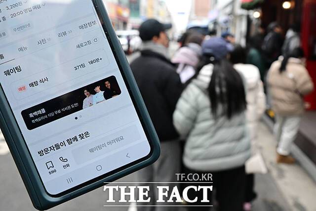 '두바이 쫀득쿠키(두쫀쿠)'가 한국에서 인기 열풍을 일으키고 있는 가운데 18일 서울 광진구 모 제빵점에서 시민들이 두쫀쿠를 구매하기 위해 줄을 서고 있다. 왼쪽은 해당 매장 이용을 위해 371팀이 웨이팅 중인 화면. /남윤호 기자