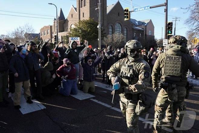 13일(현지시간) 미국 미네소타주 미니애폴리스에서 경찰과 시민들이 대치하고 있다. 일부 시민은 항의의 뜻으로 무릎을 꿇고 있다. 로이터연합뉴스