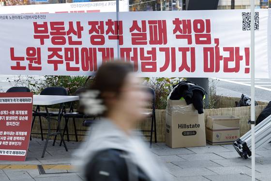 지난해 11월 22일 오후 서울 노원구 롯데백화점 사거리에 붙은 토허제 규탄 플래카드 앞으로 구민들이 지나고 있다. 뉴스1