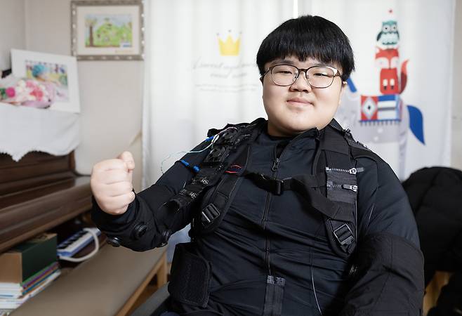 Myung Ha-yul, a student diagnosed with Duchenne muscular dystrophy, poses for a photo while wearing a wearable robotic exoskeleton developed by the Korea Institute of Machinery and Materials (KIMM) at his home in southern Seoul on Dec. 19, 2025. The KIMM and the Seoul National University Hospital are conducting clinical trials using the wearable robot, which is said to allow the wearer to lift up to 15 kilograms (33 pounds). [JUN MIN-KYU]