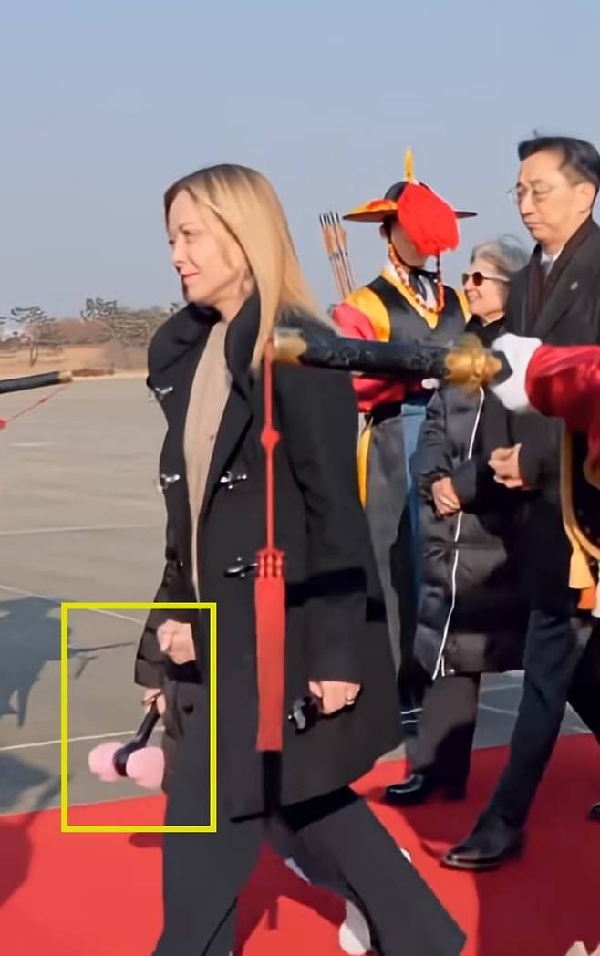 18일 서울공항을 통해 입국한 조르자 멜로니 이탈리아 총리가 10살 딸 지네브라의 손을 잡고 전용기에서 내리고 있다. 딸의 모습은 안보이지만 딸이 들고 있는 블랙핑크 응원봉(노란 사격형)이 보인다./멜로니 총리 유튜브