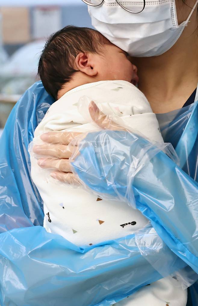 A nurse holds a newborn baby at a hospital in Goyang, Gyeonggi Province on Dec. 26. (Yonhap)