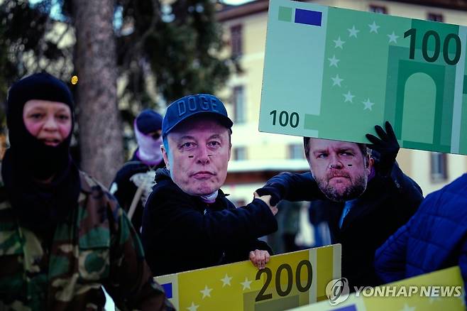 다보스포럼 반대 시위 스위스 다보스에서 열리는 세계경제포럼(WEF) 연례 총회 반대 시위에서 일론 머스크 테슬라 최고경영자(가운데)와 JD밴스 미국 부통령(오른쪽)의 가면을 쓴 사람들이 행진하고 있다. [AP=연합뉴스] 2026.1.18