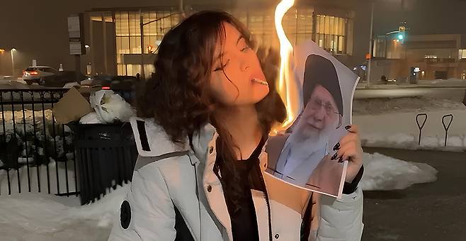 ‘모티시아 아담스’라는 예명을 쓰는 이란 난민 여성이 이란 최고지도자 아야톨라 알리 하메네이의 사진에 불을 붙인 뒤 담배에 옮겨 붙이고 있다. 모티시아 아담스 엑스 계정