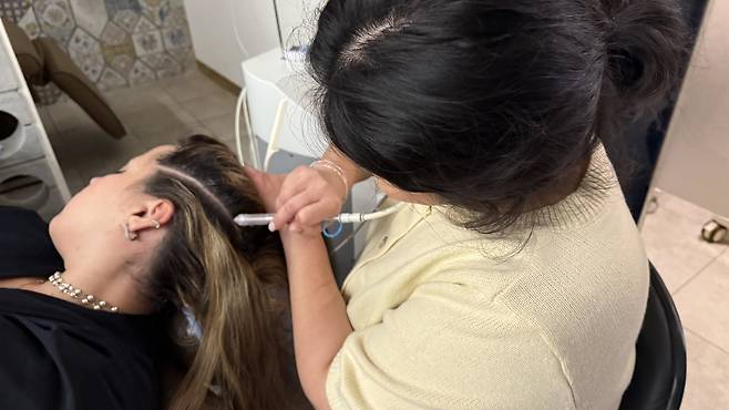 A scalp specialist cleanses an overseas customer’s scalp using a scaling device at Moclock, on Jan. 14. [WOO JI-WON]