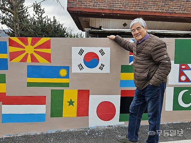 19일 오전 노의웅 화백이 광주 남구 양과동 '노의웅 미술관' 앞 담벼락에 그린 만국기 벽화를 소개하고 있다. 강주비 기자