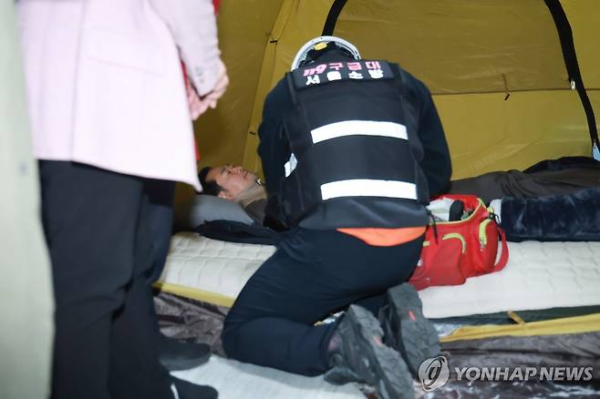 장동혁 대표 바이탈 체크하는 구급대원 (서울=연합뉴스) 신현우 기자 = 21일 국회 로텐더홀 단식 농성장에서 구급대원이 통일교·공천헌금 '쌍특검' 수용을 요구하며 이레째 단식 중인 국민의힘 장동혁 대표의 바이탈을 체크하고 있다. 2026.1.21 nowwego@yna.co.kr