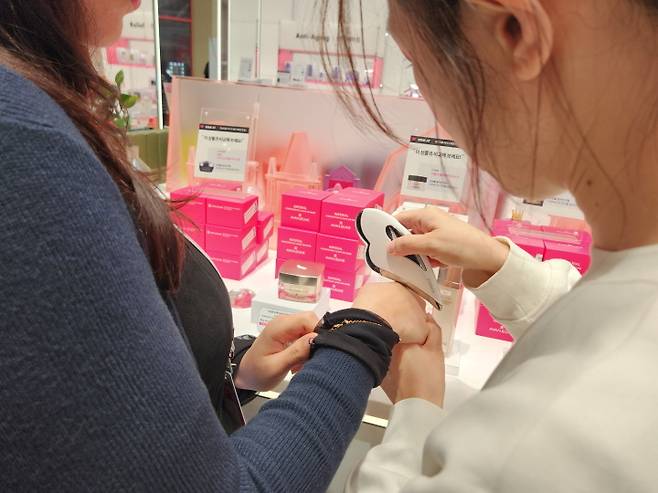 K-스타일리시 체험 프로그램에 참여한 외국인들이 매장에서 직접 자신의 피부에 적합한 화장품을 발라보고 있다.