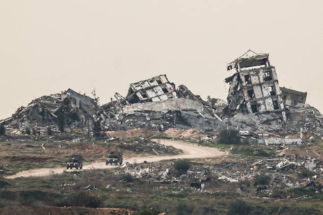Israeli military vehicles drive past destruction in Gaza, as seen from the Israeli side of the Israel-Gaza border in southern Israel on Jan. 21. [REUTERS/YONHAP]