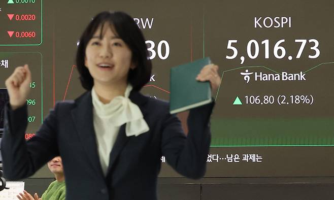 An employee at Hana Bank in central Seoul celebrates the Kospi's milestone in its dealing room in central Seoul as it surpassed the 5,000 points for the first time on Thursday. [YONHAP]